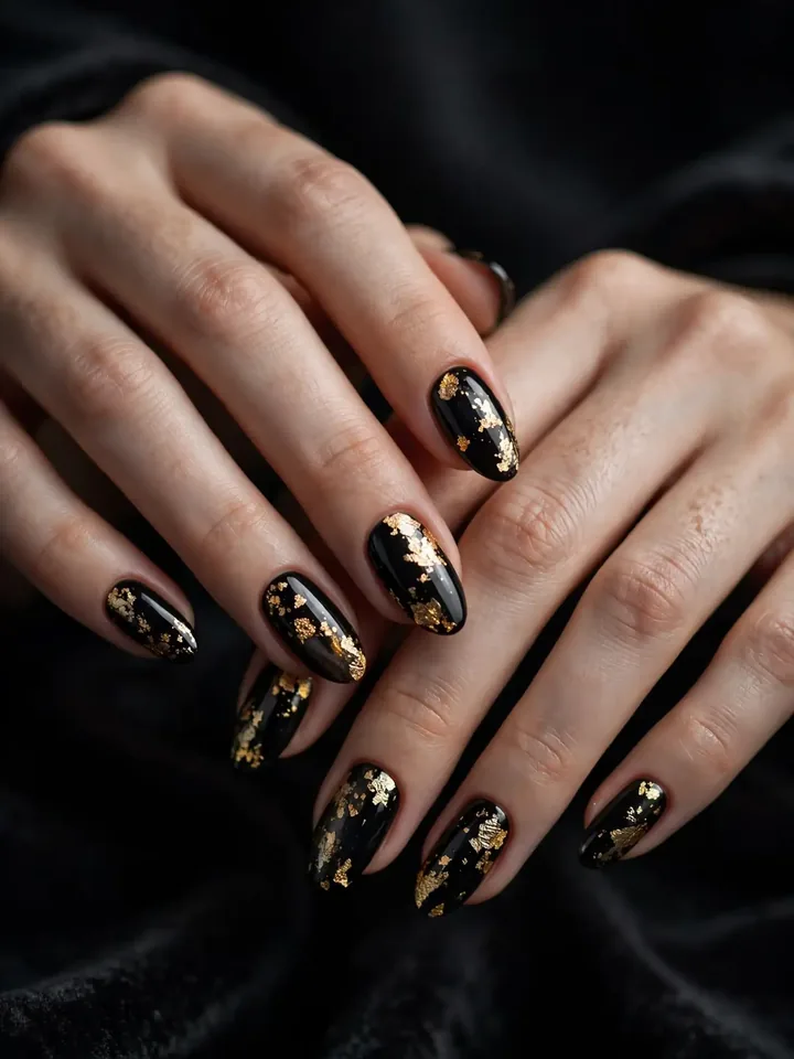 Black wedding nails with delicate gold foil flakes on glossy black almond nails