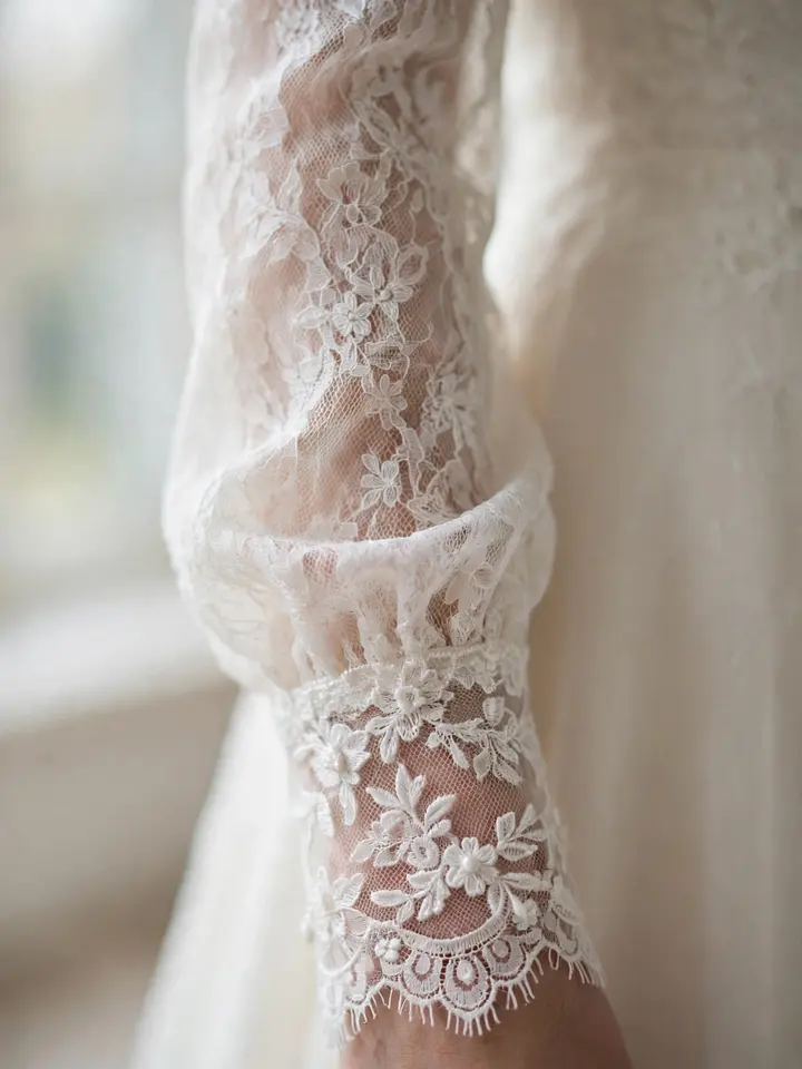 Close-up of lace cuffs on a simple lace wedding dress with elegant long sleeves