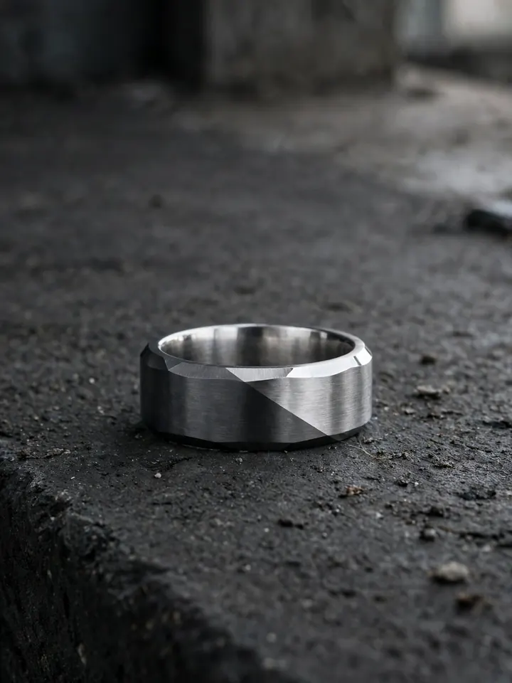 Two-tone beveled titanium wedding ring for men in gunmetal and silver on concrete